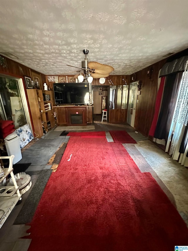 interior space with carpet, wooden walls, and ceiling fan