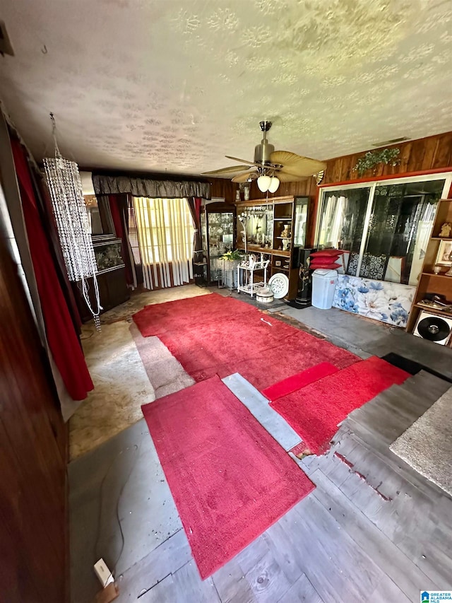 interior space featuring ceiling fan and wood walls