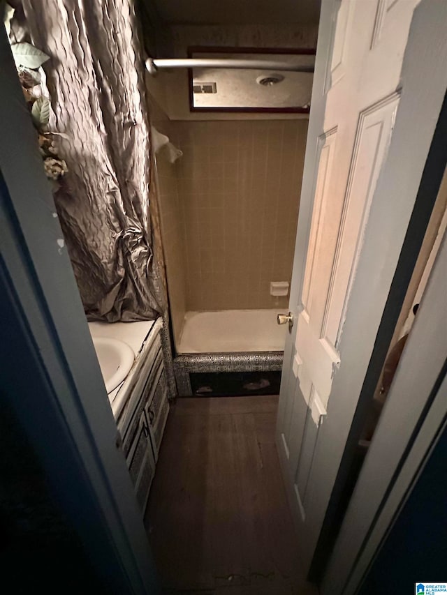 bathroom featuring wood-type flooring, vanity, and tiled shower / bath combo