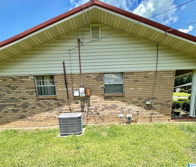 rear view of house featuring central AC and a lawn