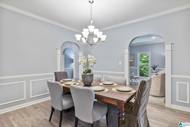 dining space with crown molding, a chandelier, and light hardwood / wood-style flooring