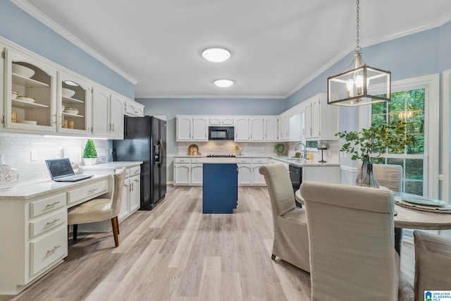 kitchen featuring ornamental molding, black appliances, a kitchen island, decorative light fixtures, and light wood-type flooring