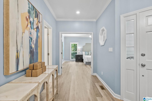 corridor with light hardwood / wood-style flooring and ornamental molding