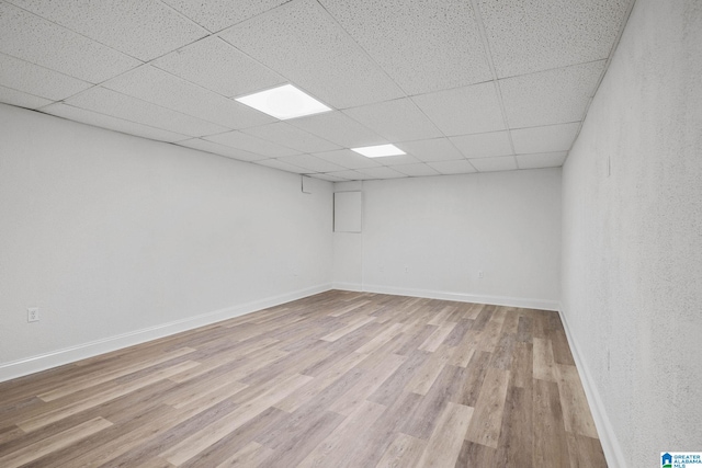 basement featuring a paneled ceiling and light wood-type flooring