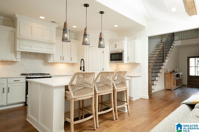 kitchen featuring tasteful backsplash, white cabinetry, a kitchen island, light hardwood / wood-style flooring, and stainless steel appliances