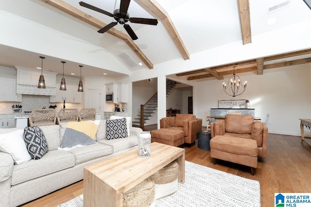 living room with vaulted ceiling with beams, ceiling fan with notable chandelier, and light hardwood / wood-style flooring