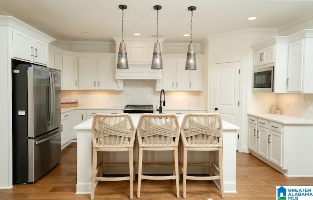 kitchen with white cabinets, a center island with sink, and appliances with stainless steel finishes