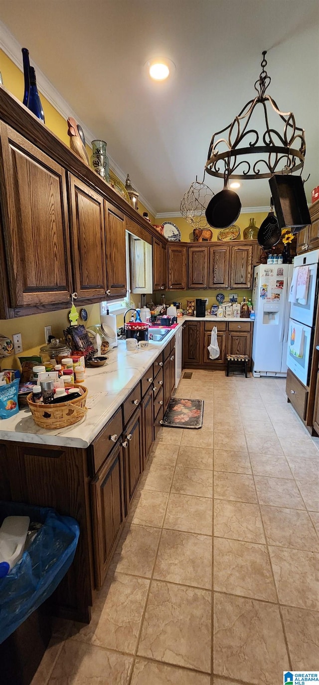 kitchen featuring light tile floors, ornamental molding, dark brown cabinets, and white refrigerator with ice dispenser