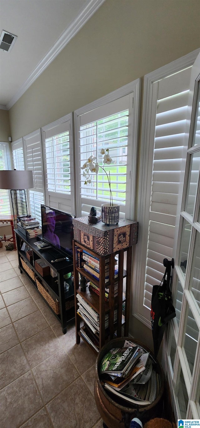 living room featuring crown molding, tile flooring, and a healthy amount of sunlight