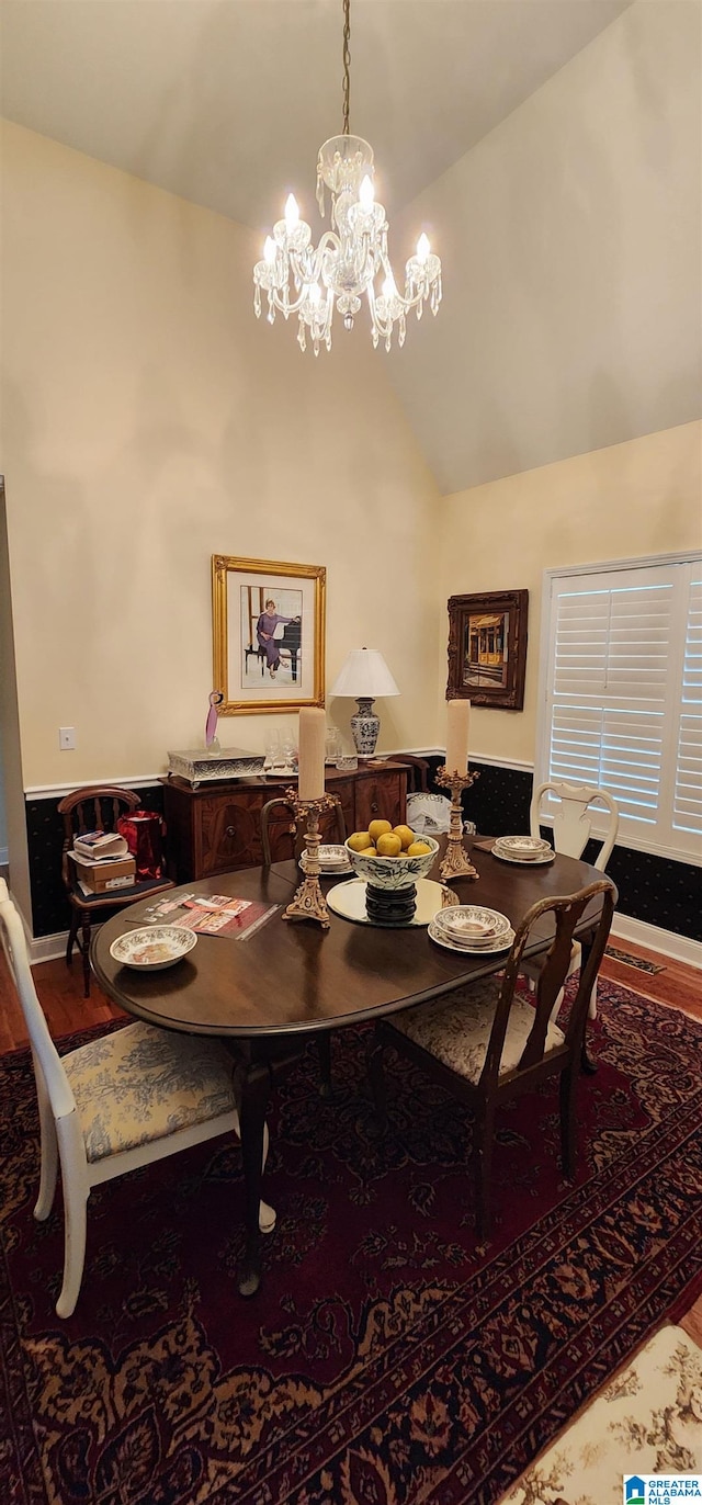 dining area with wood-type flooring, a chandelier, and lofted ceiling