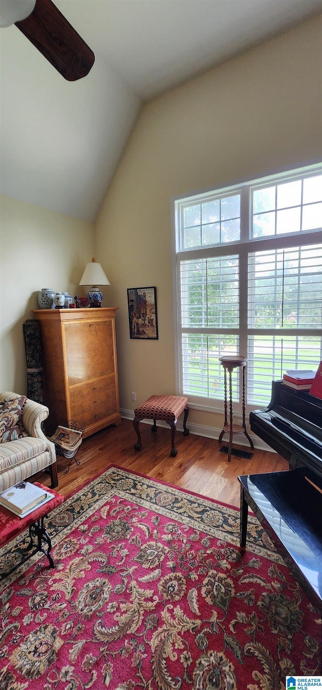 living area featuring vaulted ceiling, ceiling fan, and hardwood / wood-style flooring