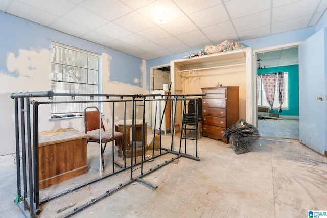 bedroom with a paneled ceiling and concrete floors