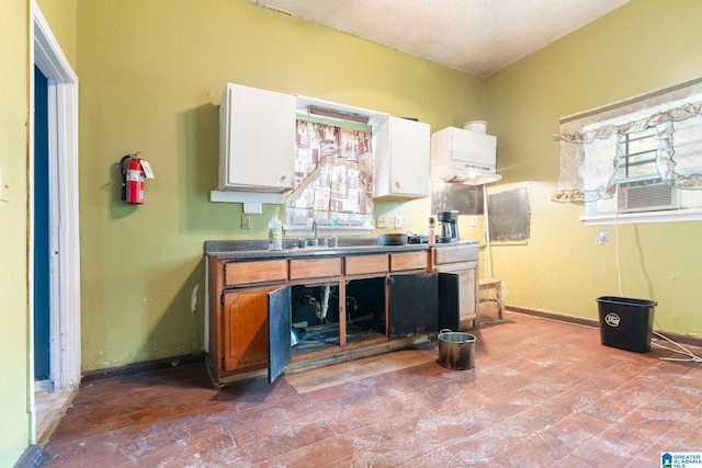 kitchen with a healthy amount of sunlight, sink, white cabinetry, and a textured ceiling