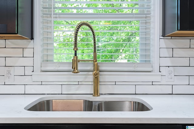 interior details featuring tasteful backsplash, light stone counters, and sink