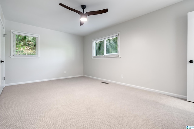 carpeted empty room with ceiling fan and a wealth of natural light