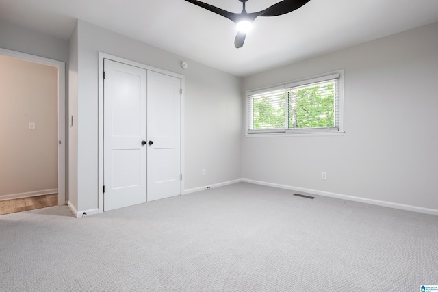 unfurnished bedroom with carpet flooring, ceiling fan, and a closet