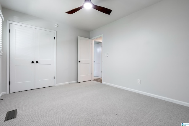 unfurnished bedroom featuring ceiling fan, light carpet, and a closet