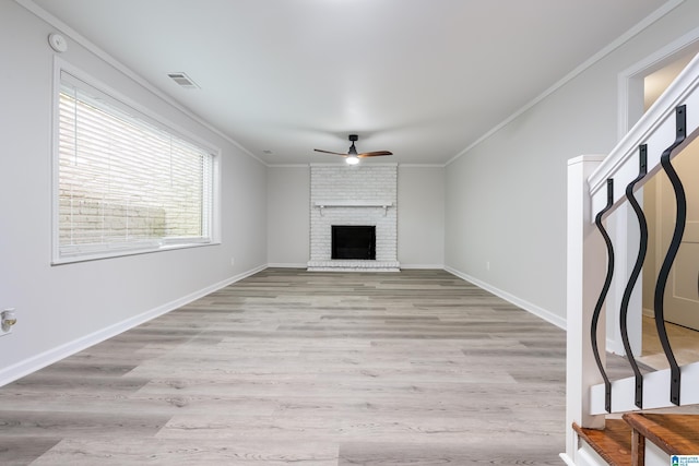 unfurnished living room featuring light hardwood / wood-style flooring, a brick fireplace, ceiling fan, and ornamental molding