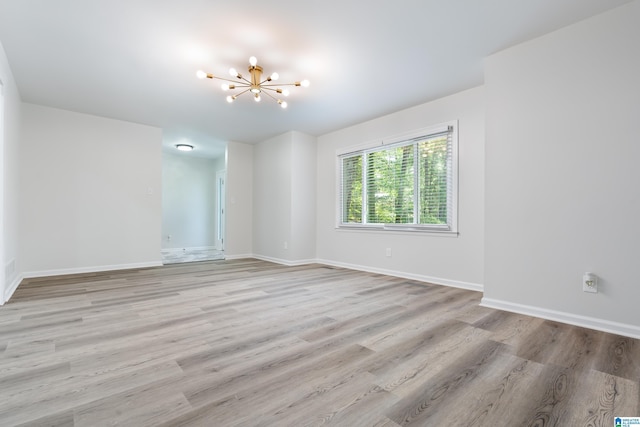 empty room with a notable chandelier and light wood-type flooring