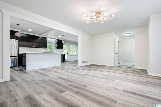 unfurnished living room with beamed ceiling, light wood-type flooring, and an inviting chandelier