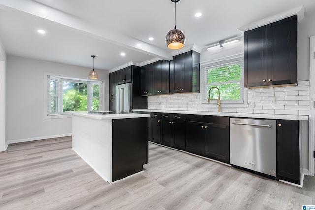 kitchen with appliances with stainless steel finishes, a kitchen island, hanging light fixtures, and a healthy amount of sunlight