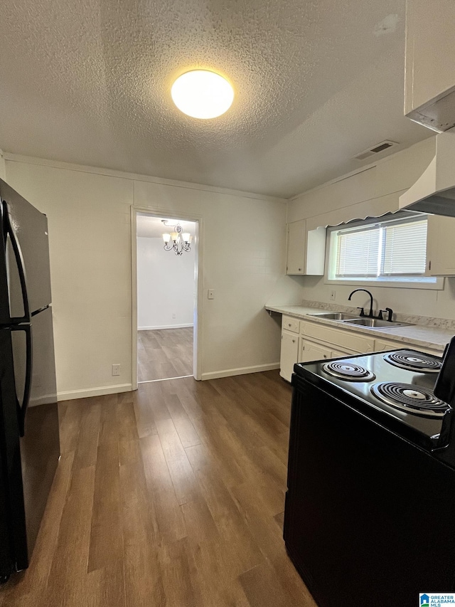 kitchen featuring black / electric stove, a textured ceiling, dark hardwood / wood-style floors, white cabinetry, and fridge