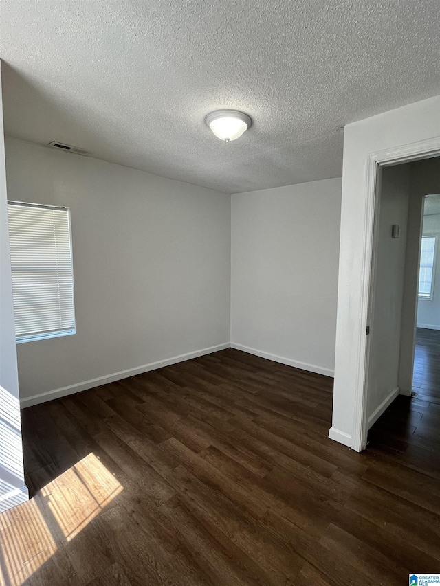 empty room with a textured ceiling and dark wood-type flooring