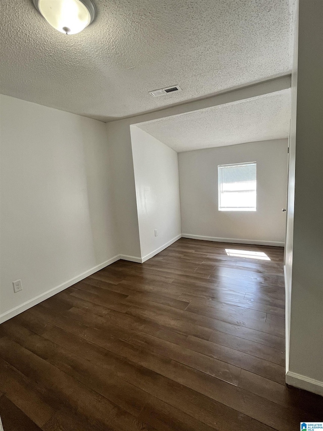 spare room featuring dark hardwood / wood-style flooring and a textured ceiling