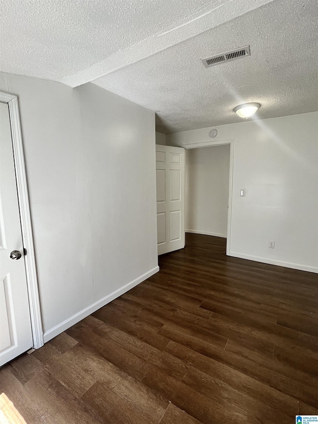 spare room with a textured ceiling and dark hardwood / wood-style floors