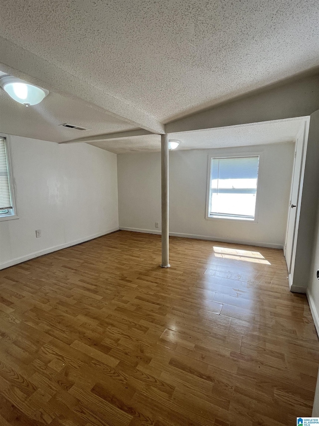 basement with hardwood / wood-style floors and a textured ceiling