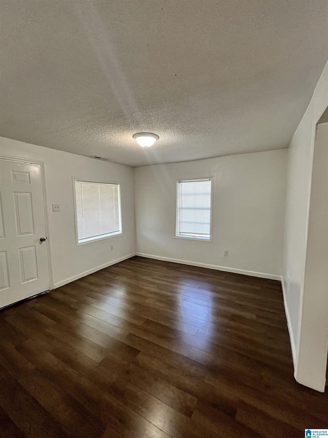 unfurnished room with a textured ceiling and dark wood-type flooring