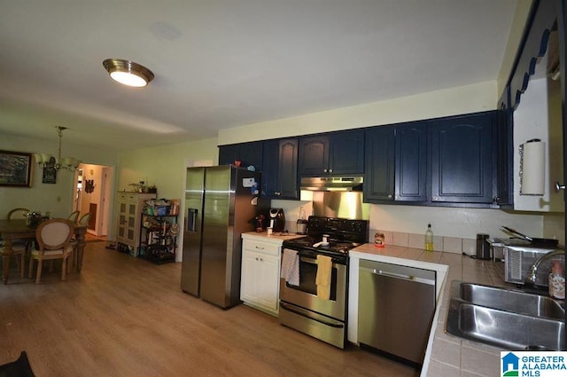 kitchen with light hardwood / wood-style floors, tile counters, an inviting chandelier, sink, and appliances with stainless steel finishes