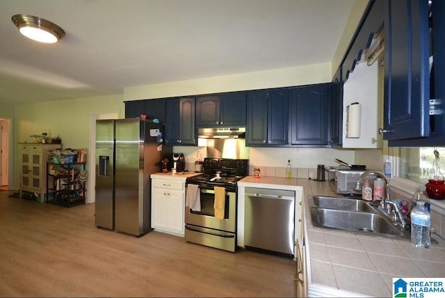 kitchen featuring light hardwood / wood-style floors, appliances with stainless steel finishes, tile countertops, sink, and blue cabinets