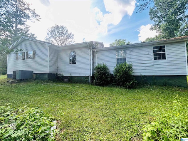 rear view of house featuring central AC and a lawn