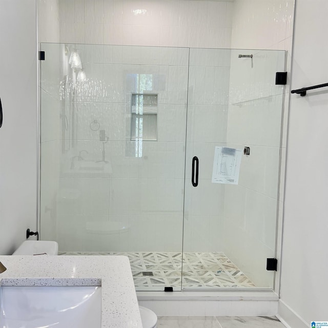 bathroom featuring a shower with door, sink, and toilet