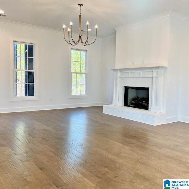 unfurnished living room with hardwood / wood-style flooring, crown molding, a fireplace, and an inviting chandelier