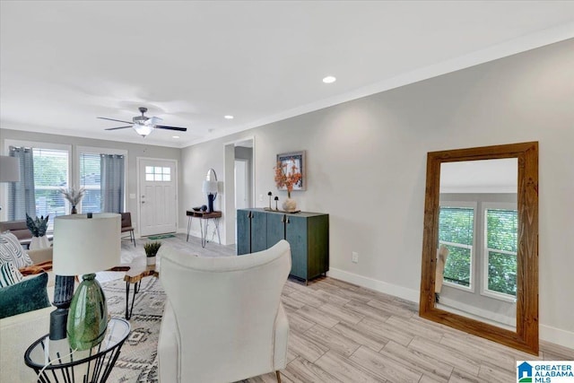 living room featuring light hardwood / wood-style flooring, ceiling fan, and ornamental molding