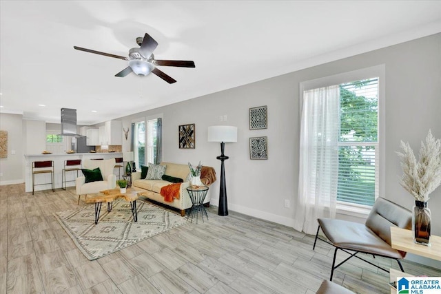 living room with ceiling fan, crown molding, and light hardwood / wood-style flooring