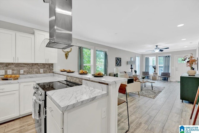 kitchen with a breakfast bar, ceiling fan, light stone countertops, high end stove, and white cabinetry