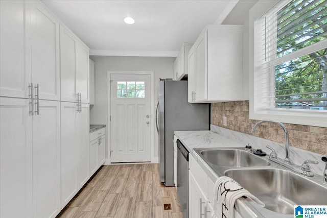 kitchen featuring light stone countertops, sink, tasteful backsplash, stainless steel dishwasher, and white cabinets