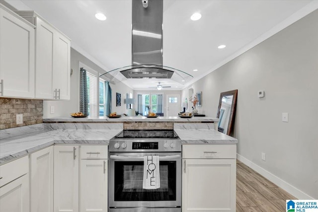 kitchen with island exhaust hood, light stone countertops, stainless steel electric range oven, crown molding, and white cabinetry