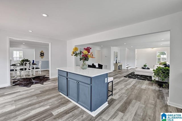 kitchen with a kitchen breakfast bar, a center island, light hardwood / wood-style flooring, and a healthy amount of sunlight