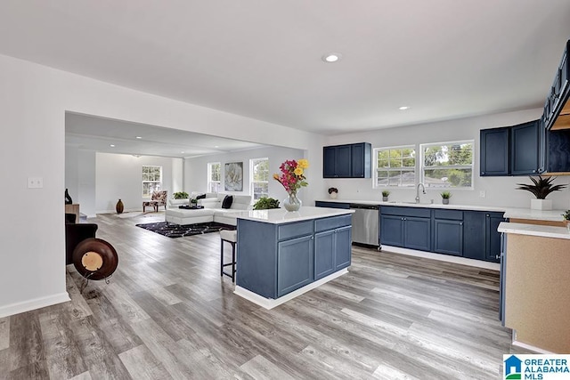 kitchen featuring dishwasher, a kitchen bar, light wood-type flooring, and a wealth of natural light