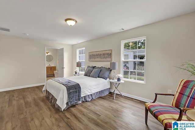 bedroom with wood-type flooring and connected bathroom