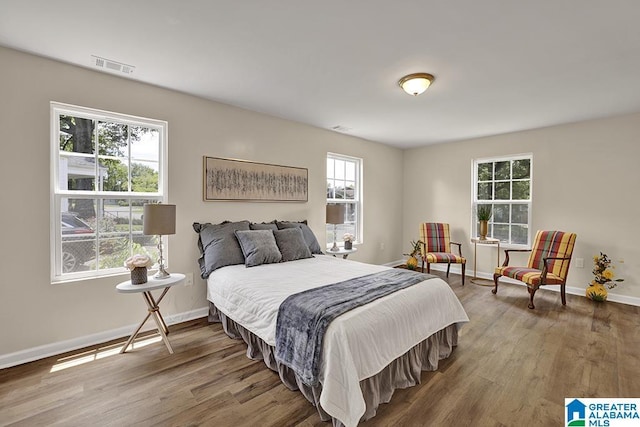 bedroom with multiple windows and hardwood / wood-style flooring