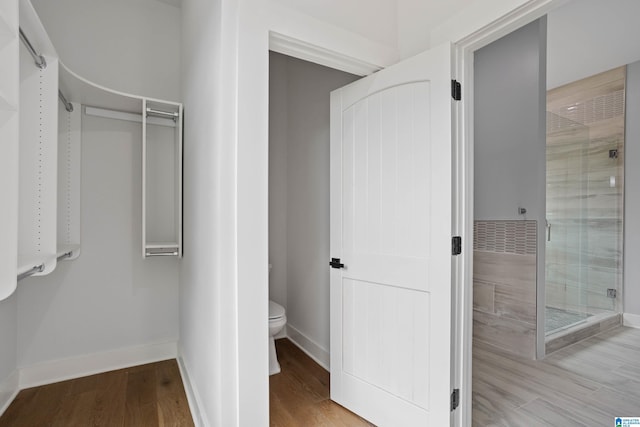 bathroom featuring hardwood / wood-style floors, toilet, and walk in shower