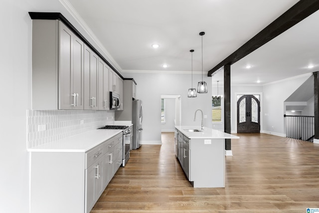 kitchen with gray cabinetry, sink, a center island with sink, and appliances with stainless steel finishes