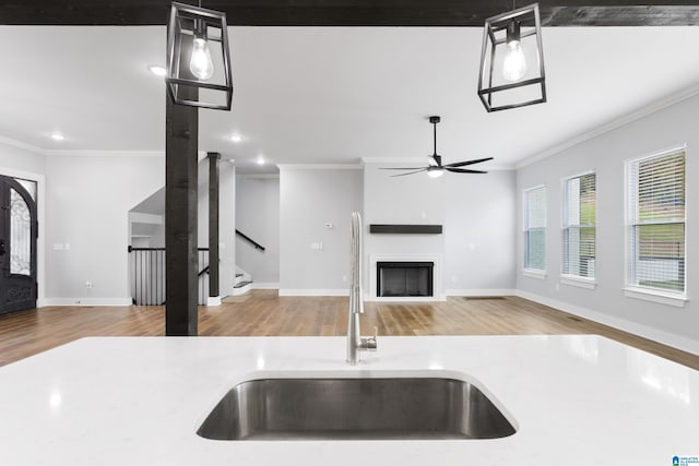 kitchen featuring crown molding, decorative light fixtures, sink, and hardwood / wood-style floors