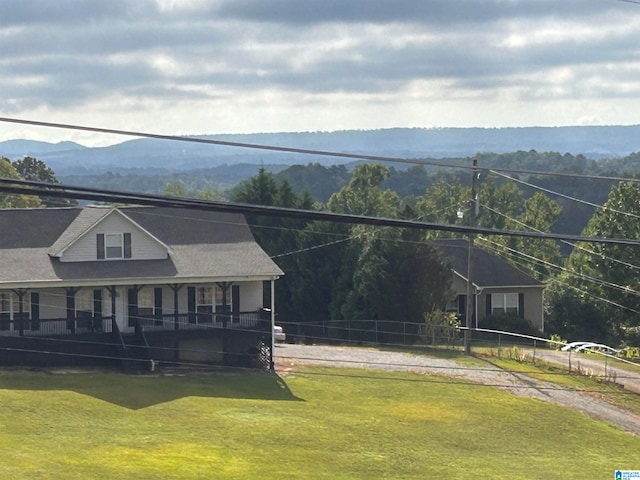 view of front facade with a mountain view, covered porch, and a front lawn