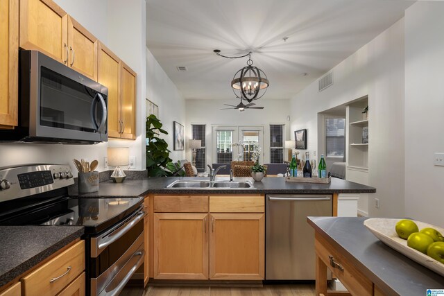 kitchen featuring stainless steel appliances, kitchen peninsula, track lighting, and dark wood-type flooring